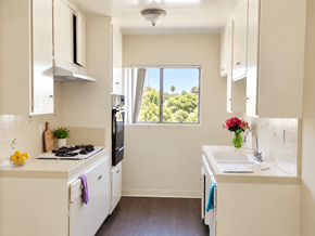 Inglewood apartment for rent - A kitchen with white cabinets and a window overlooking trees.