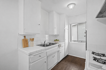 Huntington Park apartment for rent - A white kitchen with a wooden cutting board and utensils on the counter.