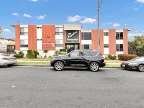 Inglewood apartment for rent - A black SUV is parked in front of a building with a sign that says "Now Leasing.".