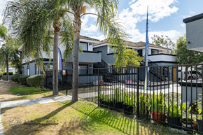 Orange apartment for rent - A building with a black fence and a flag on top.