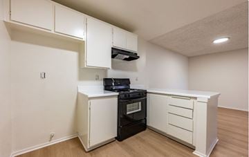 Pomona apartment for rent - A kitchen with a black stove top oven and white cabinets.