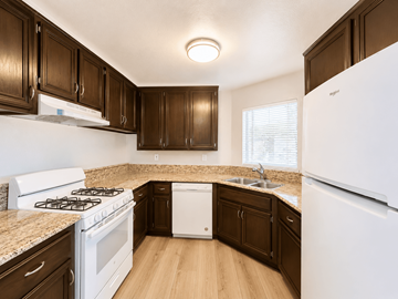Long Beach apartment for rent - A kitchen with white appliances and brown cabinets.