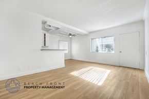 Huntington Park apartment for rent - A spacious room with wooden floors and white walls, with a window covered by blinds.