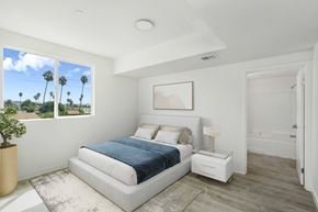 Los Angeles apartment for rent - A bedroom with a large bed and a view of palm trees outside the window.