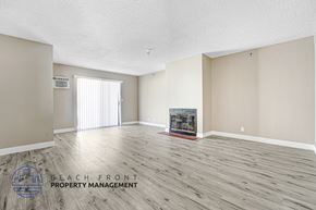 Hawthorne apartment for rent - A spacious room with a fireplace and a logo for Beach Front Property Management.