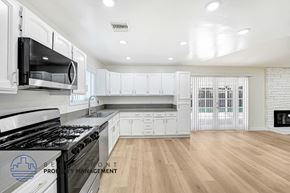 Granada Hills apartment for rent - A modern kitchen with white cabinets and a black stove top.