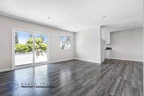 Hawthorne apartment for rent - A spacious room with wooden flooring and a view of the beach through the sliding glass doors.