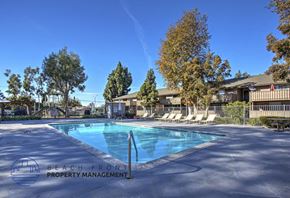 Garden Grove apartment for rent - A pool surrounded by trees and chairs with a sign that says Beach Front Property Management.