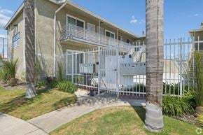 Gardena apartment for rent - A white gate surrounds a building with a blue sign on it.