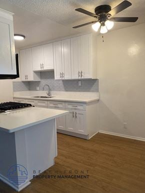 Buena Park apartment for rent - an empty kitchen with white cabinets and a ceiling fan