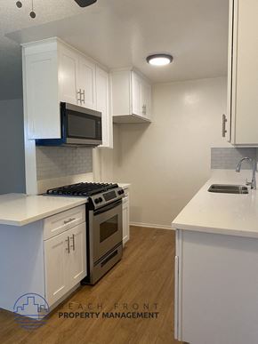 Buena Park apartment for rent - an empty kitchen with white cabinets and a stove and microwave