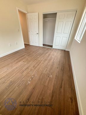 Whittier apartment for rent - A room with wooden floors and white walls, with a logo for Beachfront Property Management in the bottom left corner.