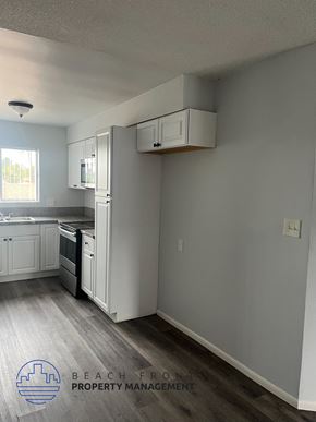 Long Beach apartment for rent - A kitchen with white cabinets and a black stove top oven.