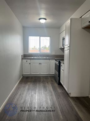 Long Beach apartment for rent - A kitchen with white cabinets and a wooden floor.