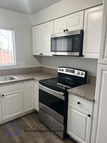 Long Beach apartment for rent - A kitchen with a black stove top oven and a black microwave above it.