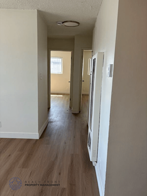 Torrance apartment for rent - A long hallway with a logo for Beach Front Property Management in the bottom left corner.