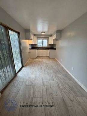 Los Angeles apartment for rent - A spacious room with wooden flooring and a kitchen area in the background.