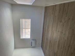 Huntington Park triplex for rent - living room with a window and a wooden wall