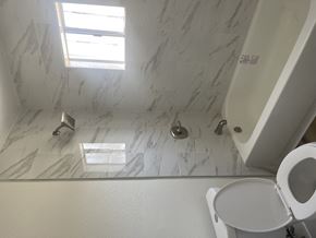 Huntington Park triplex for rent - a white bathroom with a toilet and a tub and a window