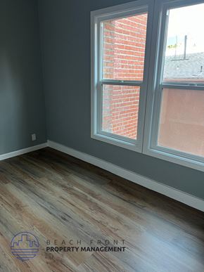 Los Angeles apartment for rent - A room with a wooden floor and a window showing a brick wall outside.