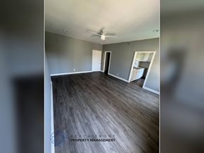 Los Angeles apartment for rent - A spacious room with wooden flooring and a ceiling fan is on the market.