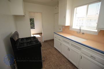 San Pedro apartment for rent - A kitchen with white cabinets and a black trash can.