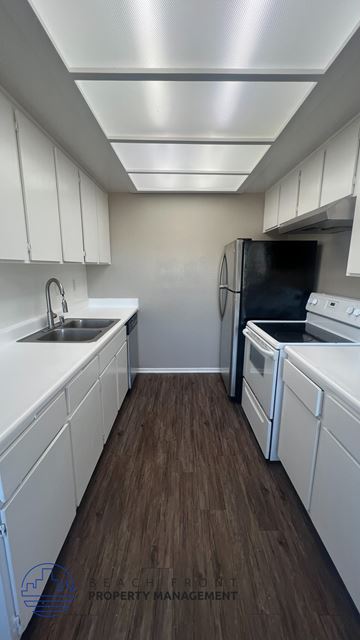 San Pedro apartment for rent - A kitchen with white cabinets and a black fridge.
