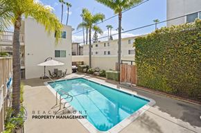 Torrance apartment for rent - A pool surrounded by a patio and palm trees.