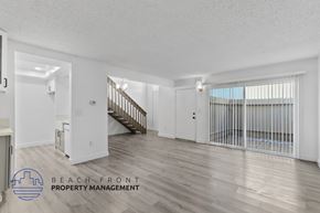 Anaheim apartment for rent - A spacious room with wooden floors and a staircase leading to another room.