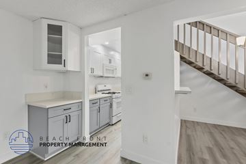Anaheim apartment for rent - A kitchen with white cabinets and a staircase in the background.