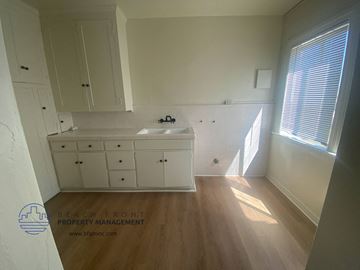 San Pedro apartment for rent - a small kitchen with white cabinets and a sink and a window