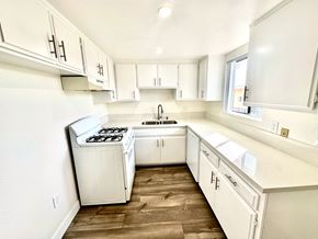 Los Angeles apartment for rent - an empty kitchen with white cabinets and a window