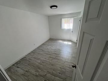 Santa Ana apartment for rent - A room with a wooden floor and a door on the right side.