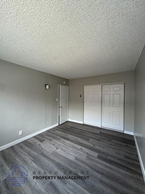 Long Beach apartment for rent - an empty living room with a white door and wood floors