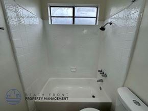 Los Angeles apartment for rent - A white tiled bathroom with a window and a bathtub.