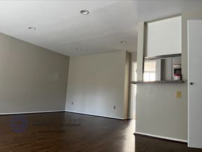 Los Angeles apartment for rent - A spacious room with wooden floors and white walls, with a door on the right side.