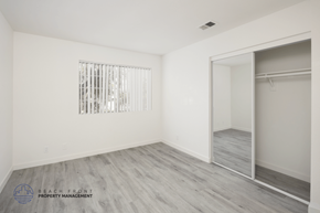 Orange apartment for rent - A sparsely furnished room with a sliding door and a window with bars.