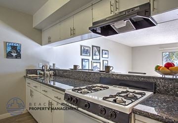 Garden Grove apartment for rent - A kitchen with a stove top oven and a bowl of fruit on the counter.