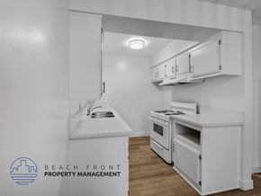 Inglewood apartment for rent - A kitchen with white cabinets and a logo for Beach Front Property Management.