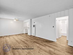 Inglewood apartment for rent - A spacious room with wooden flooring and white walls, with a logo for Beach Front Property Management in the bottom left corner.
