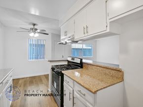 Long Beach apartment for rent - A kitchen with a black stove top oven and a counter top with a brown granite counter top.