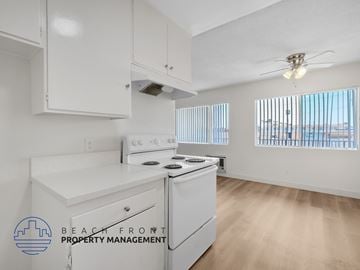 Inglewood apartment for rent - A kitchen with white appliances and cabinets with a logo for Beach Front Property Management.