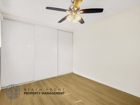 Downey apartment for rent - A room with a ceiling fan and a logo for Beach Front Property Management.