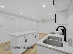 Long Beach apartment for rent - A modern kitchen with a sink and a logo for Beach Front Property Management.
