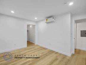 Long Beach apartment for rent - A spacious room with wooden flooring and a white wall with a window.
