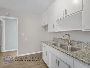 Long Beach apartment for rent - A kitchen with white cabinets and a granite countertop.