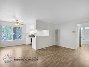 Harbor City apartment for rent - A spacious room with wooden flooring and a ceiling fan, with a window showing trees outside.