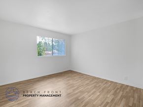 Harbor City apartment for rent - A room with wooden flooring and a window showing a view of trees and a fence.