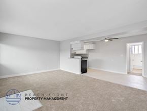Long Beach apartment for rent - A spacious room with a carpeted floor and a ceiling fan, managed by Beach Front Property Management.