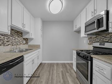 Long Beach apartment for rent - A kitchen with white cabinets and a stone backsplash.
